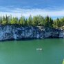 Чистая вода в карьере с красивыми скалами и зелеными деревьями под ярким небом в летний день - превью 1