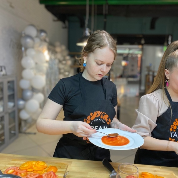 Женщина на кулинарном мастер-классе аккуратно сервирует томаты на тарелке в уютной студии в центре города. Фото 10