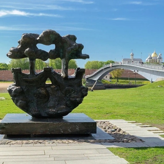 Скульптура на зеленом склоне рядом с мостом, городская зона с историческими зданиями, прекрасная погода. Фото 8