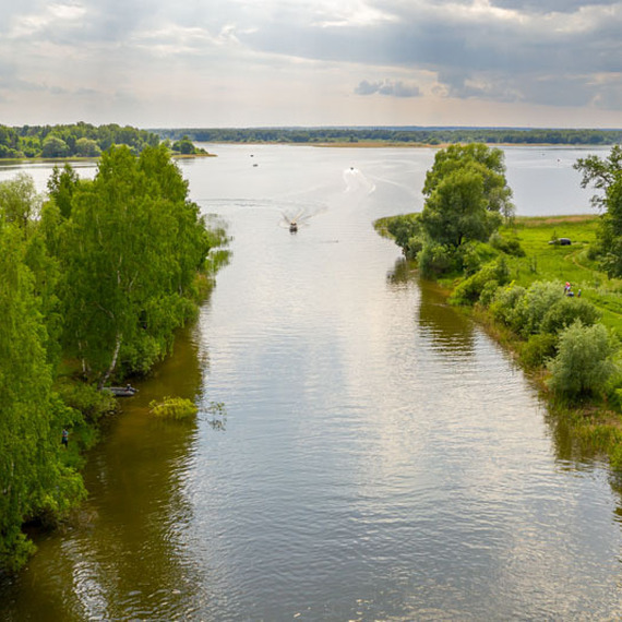 Спокойная река с зелеными берегами и лодкой летом на закате. Фото 12