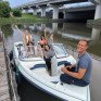 Группа людей на моторной лодке в реке под мостом во время прогулки - превью 1