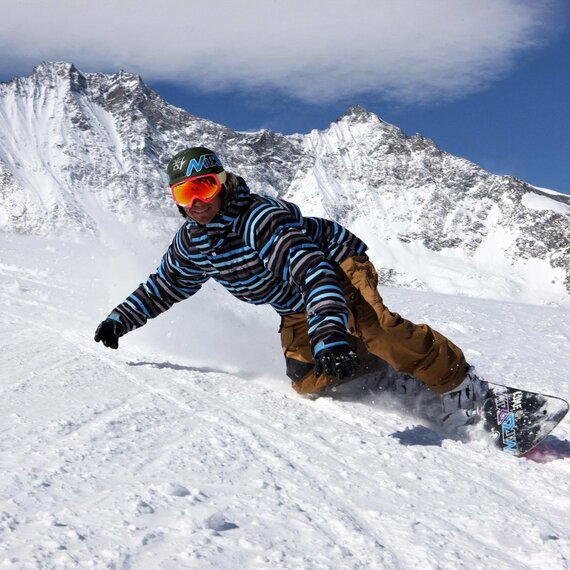На заснеженных склонах горного района человек катается на сноуборде под ясным небом в солнечный зимний день