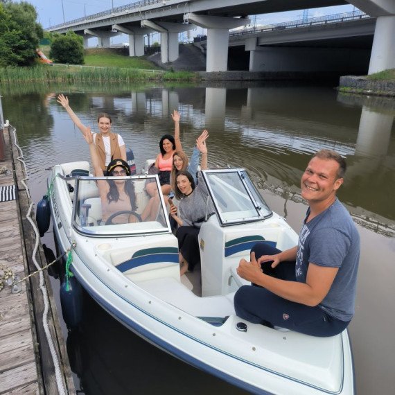 Группа людей на моторной лодке в реке под мостом во время прогулки. Главное фото