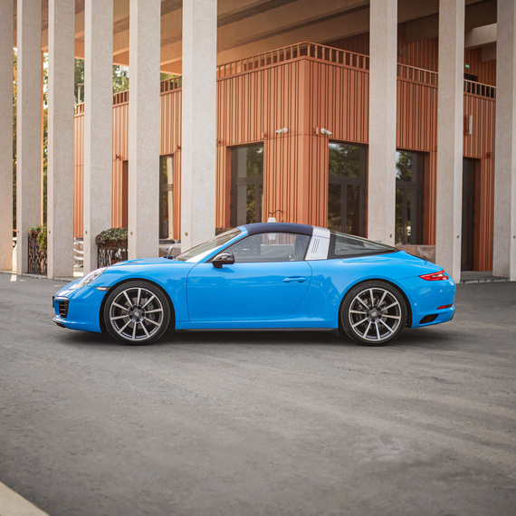 Яркая машина стоит рядом с современным зданием на улице в ясный день