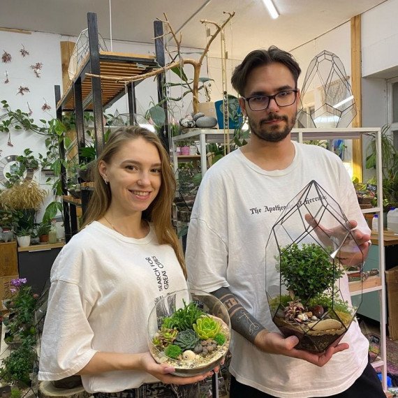 Молодые люди держат террариумы с растениями в цветочном магазине. Главное фото