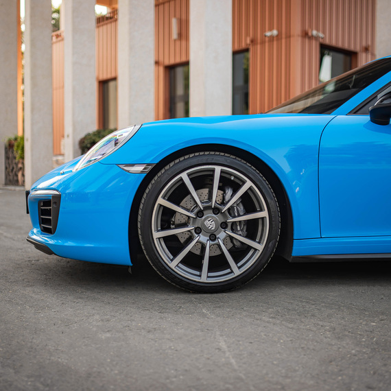 Синий автомобиль стоит на асфальте рядом с зданием в ясный день