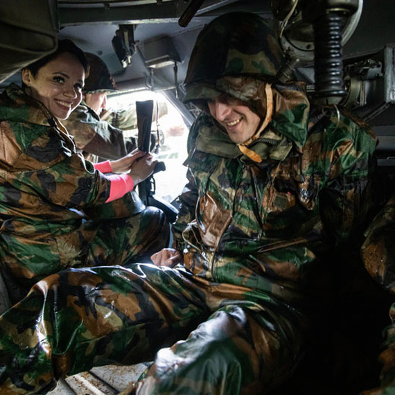 Военные в camo украшенных костюмах на учениях в закрытой машине, погруженные в обсуждение стратегии в условиях дождя. Фото 23