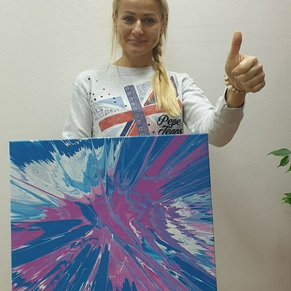 Молодая женщина с картиной в руках демонстрирует результаты своих художественных трудов в студии. Фото 6