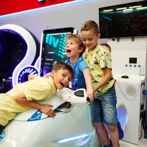 Дети играют в аркадные игры в игровом зале в центре города в выходной день Дети играют в аркадные игры в игровом зале в центре города в выходной день