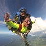 Парашютный прыжок с инструктором на фоне неба и облаков над живописным пейзажем - превью 1