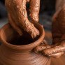 Руки формируют глиняный горшок на гончарном круге в мастерской - превью 1
