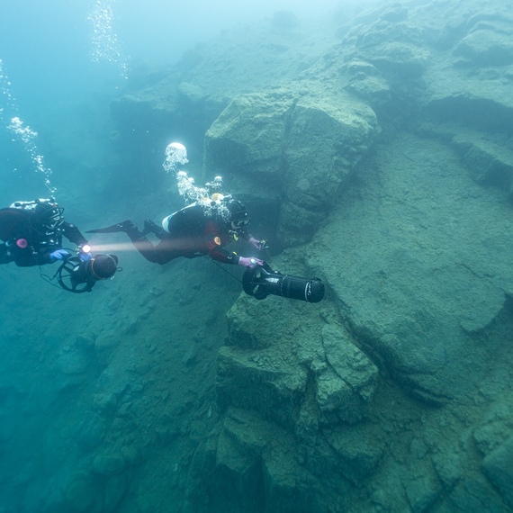 Подводные исследователи изучают морское дно в прозрачных водах на глубине восемь метров