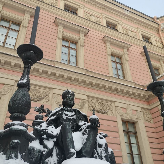 Памятник сидящему царю в зимний день, украшенный снежным покровом, на фоне исторического здания. Фото 12
