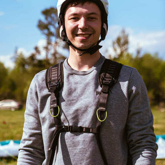 Молодой человек в шлеме готовится к парапланеризму на зеленом поле в солнечный день. Фото 13