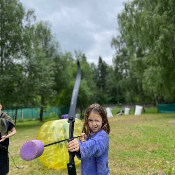 Девочка стреляет из лука на спортивной площадке на свежем воздухе. Фото 8