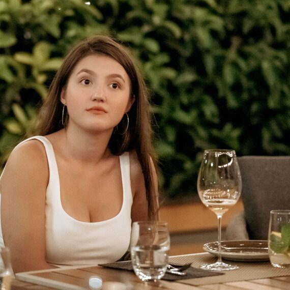 Женщина поднимает бокал с вином на праздничном обеде в уютном ресторане. Главное фото