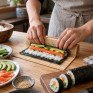 Суши с креветкой и огурцом на черной тарелке в ресторане, подаются руками с палочками - превью 1