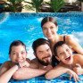 Семья проводит время в бассейне на отдыхе с детьми в яркий солнечный день - превью 1