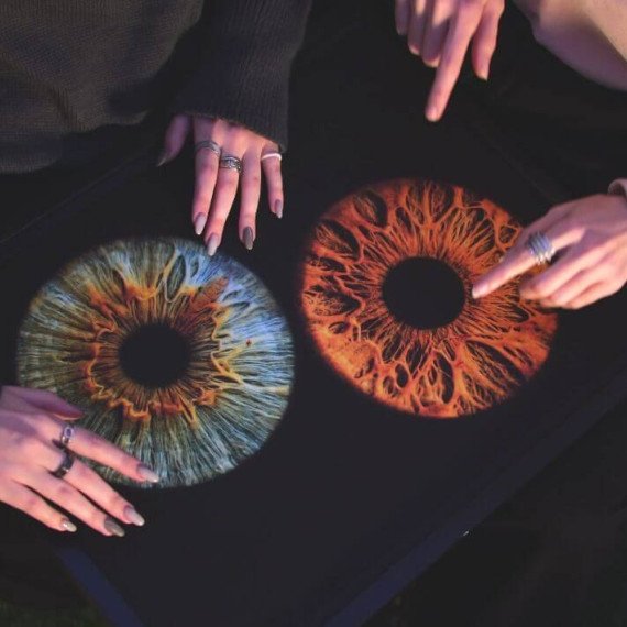 Люди рассматривают изображения глаз с разными цветами и текстурами в вечернее время