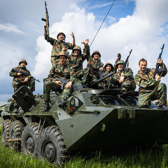 Военные на бронетранспортере в полевых условиях, улыбаются и демонстрируют оружие на фоне облачного неба. Фото 16