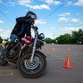 Мотоциклист на практике управления в тренажерном центре, маневрирование между конусами под ясным небом - превью 1