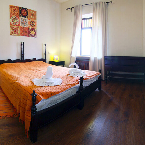 Уютная спальня с оранжевым покрывалом и декоративными элементами в солнечном помещении