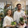 Молодые люди держат террариумы с растениями в цветочном магазине - превью 1