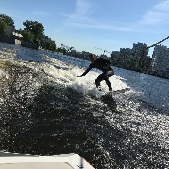 Серфер на водном лыжном канале в городе, наслаждающийся солнечным днем и легким ветром Серфер на водном лыжном канале в городе, наслаждающийся солнечным днем и легким ветром