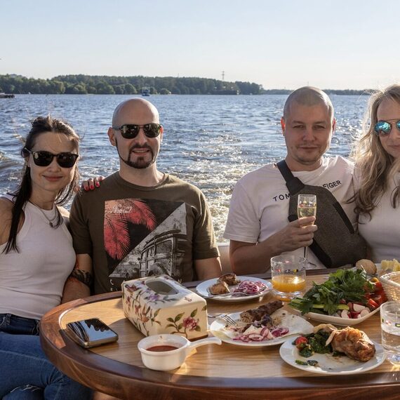 Друзья отдыхают на яхте, наслаждаясь вкусной едой и напитками на фоне озера в солнечный день. Фото 7