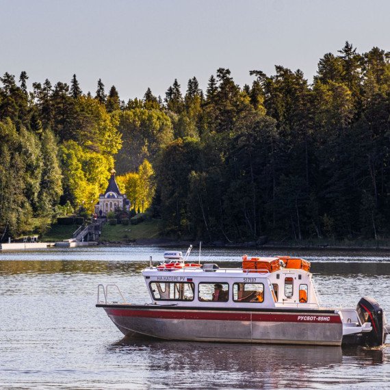 Лодка движется по воде рядом с островом и лесом в солнечный день