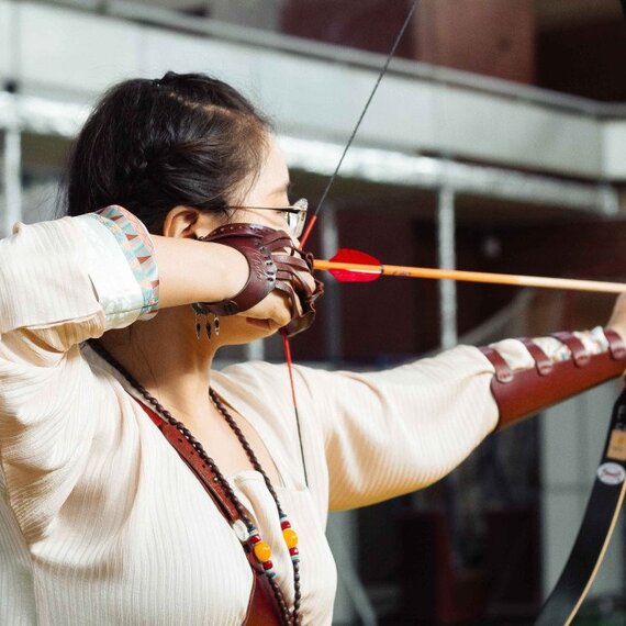 Стрельба из лука в спортивном зале с участием женщины, метящей в мишень