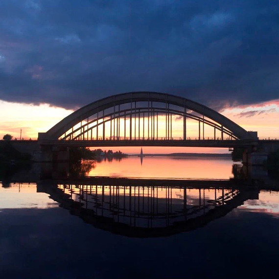 Мост на закате с отражением в реке, кадр с водной поверхности при вечернем свете, удаление от города. Фото 6