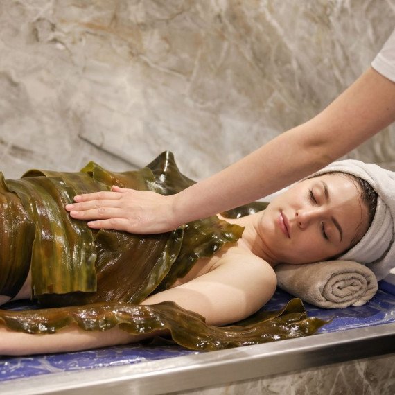 Женщина получает спа-процедуру с водорослями в спа-салоне в вечернее время