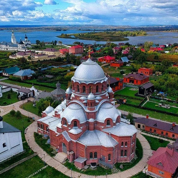Вид на историческую церковь и окрестности вдоль реки в солнечный день, зеленые луга и дома. Фото 12