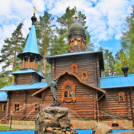 В красивом лесу стоит деревянная церковь с уникальной архитектурой и голубой крышей