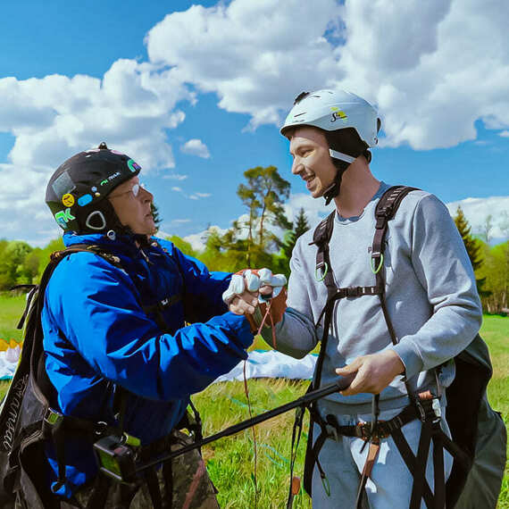 Парапланеристы на старте: подготовка к полету на фоне голубого неба и облаков