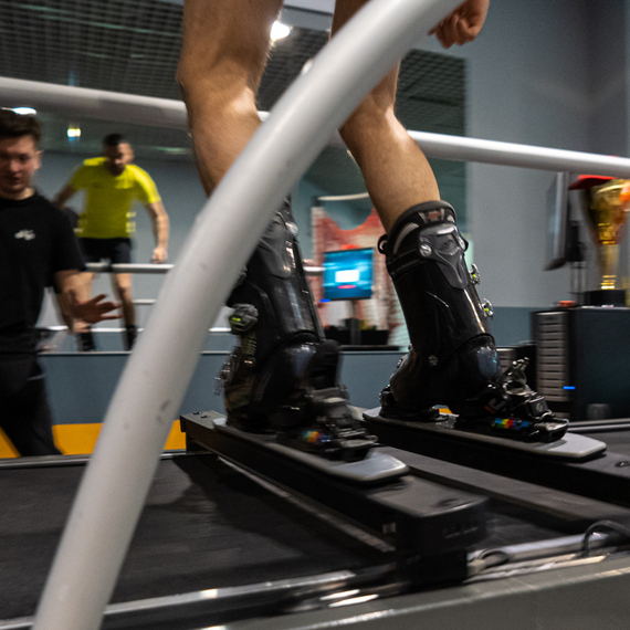 Тренировка спортсмена на специализированном беговом дорожке с лыжами в спортивном центре Тренировка спортсмена на специализированном беговом дорожке с лыжами в спортивном центре