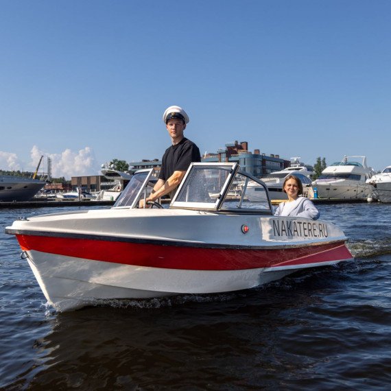 Человек и женщина на моторной лодке по реке с другими яхтами на фоне