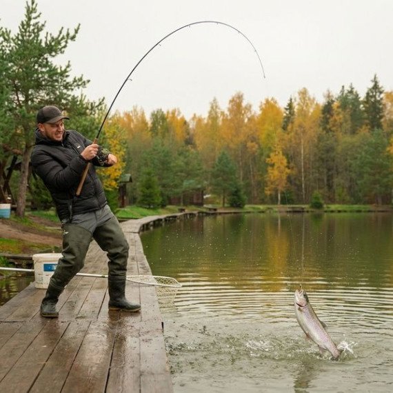 Рыбак ловит рыбу осенью на озере в лесу. Главное фото