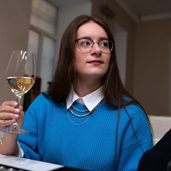 Женщина поднимает бокал с вином на праздничном обеде в уютном ресторане. Главное фото