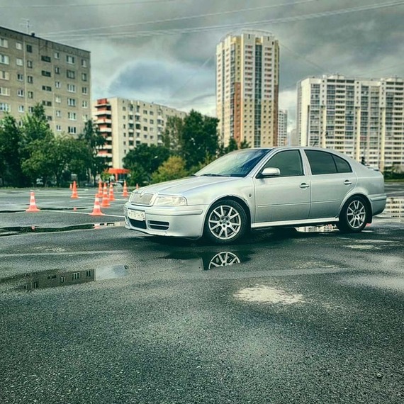 Серебристый автомобиль на мокрой площадке в городском районе после дождя. Фото 4
