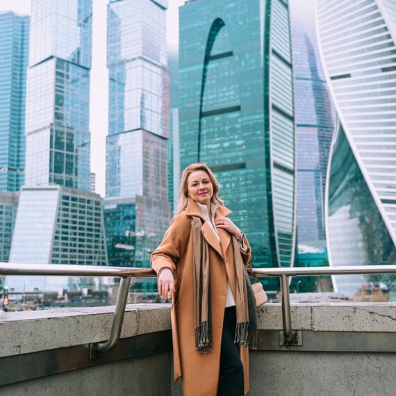 Женщина стоит на смотровой площадке с видом на небоскребы в Москве в облачный день