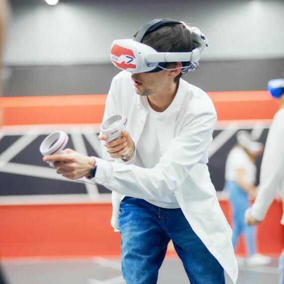 Люди играют в виртуальную реальность в игровом центре, используя VR-гарнитуры и контроллеры, вечернее время. Фото 10