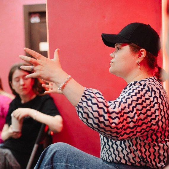 Женщина делится мыслями во время обсуждения в группе молодых людей в помещении