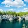 Чистая вода в карьере с красивыми скалами и зелеными деревьями под ярким небом в летний день - превью 1