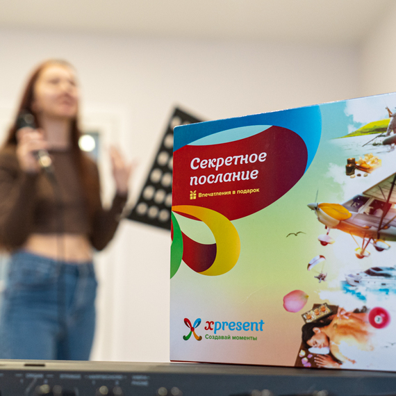 Участие человека в занятии по караоке с яркой упаковкой подарка на переднем плане в уютной комнате. Фото 8
