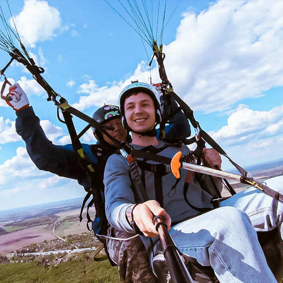 Парапланеризм над живописными холмами в ясный день с замечательными облаками и широкими просторами