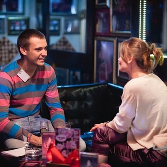 Два человека общаются в уютном баре, освещенном мягким светом, в вечернее время, создавая атмосферу дружеского разговора