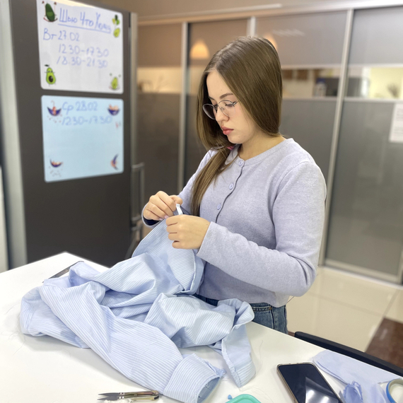 Молодая женщина ремонтирует одежду в ателье, находясь на работе в офисной обстановке. Фото 9