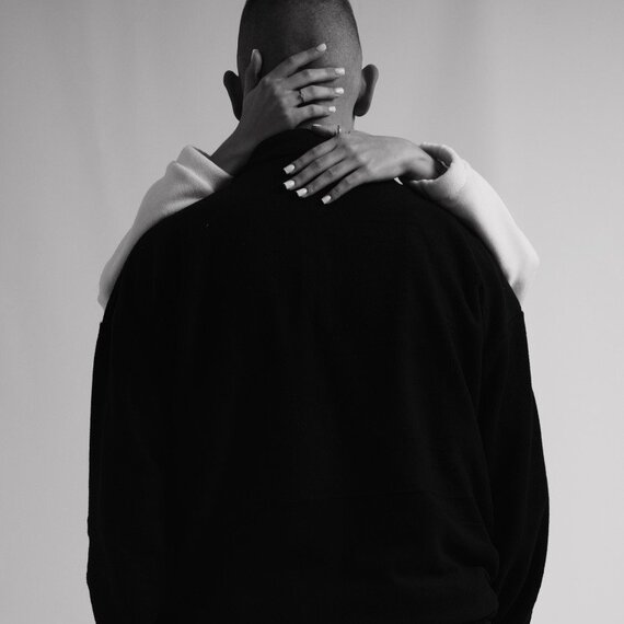 Объятия пары на фоне нейтральной стены в черно-белом цвете, символизирующие близость и доверие